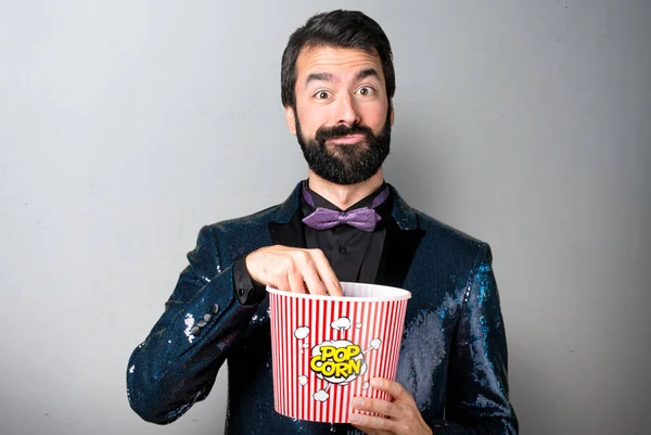 Popcorns gri arka plan üzerinde yemek payet ceket ile yakışıklı adam