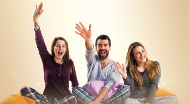 Bir yatak selamlayan üzerinde üç arkadaş