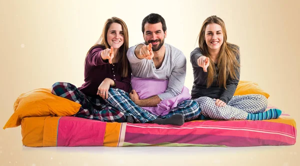 Öne doğru işaret eden bir yatakta üç arkadaş