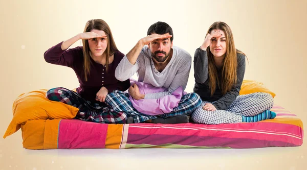 Üç arkadaş bir yatakta bir şeyler gösteriyor