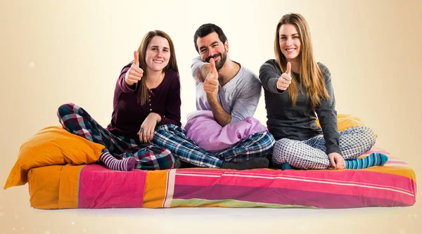 Three friends on a bed with thumb up