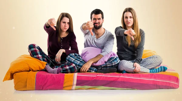 Three friends on a bed doing bad signal