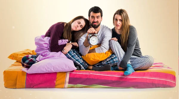 Three friends on a bed holding vintage clock