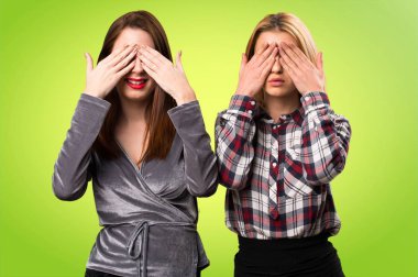 Gözleri renkli arka plan üzerinde kapsayan iki arkadaş