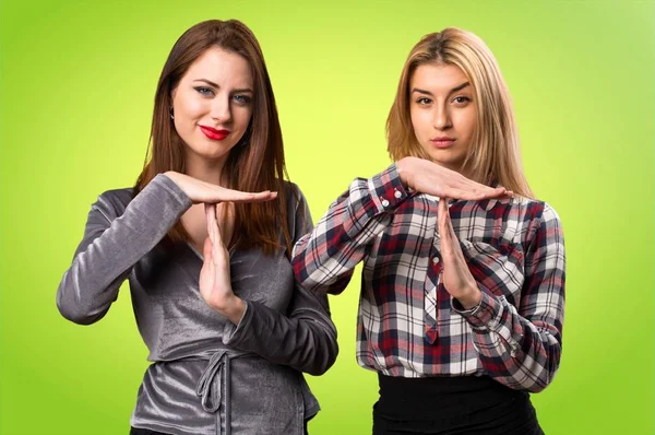 İki arkadaş dışarı jest renkli arka plan üzerinde zaman yapma