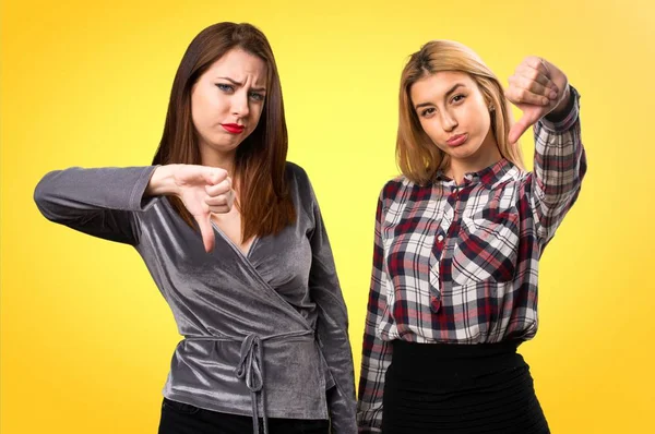 Two friends making bad signal on colorful background