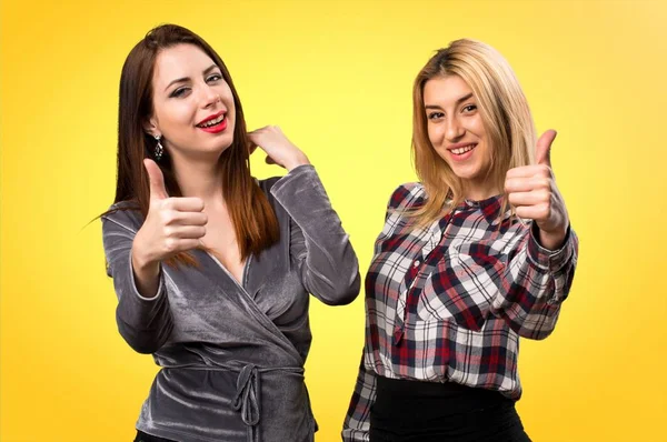 İki arkadaş renkli arka plan üzerinde başparmak ile