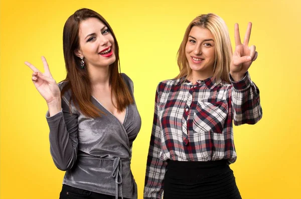 İki arkadaş zafer yapma jest renkli arka plan üzerinde