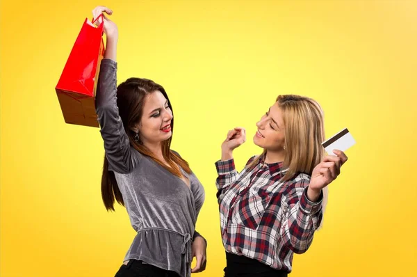 Two friends with shopping bag and credit card on colorful background