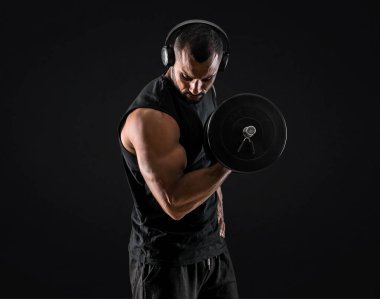 Halter yapmak, müzik dinlemek ve pazı izole siyah arka plan üzerinde egzersiz güçlü yakışıklı spor adamı