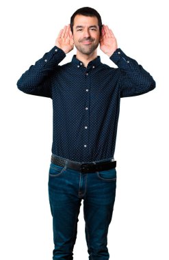 Yakışıklı adam izole beyaz arka planda bir şey dinleme