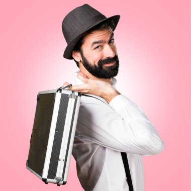 Bir evrak çantası renkli arka plan üzerinde tutarak sakallı hippi adam