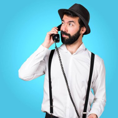 Renkli arka plan üzerinde konuşmak için vintage telefon sakallı hippi adam