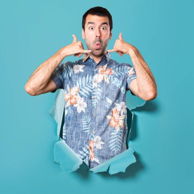 Bir mavi kağıt delikten çiçek gömlek yapma telefon hareketi ile yakışıklı adam