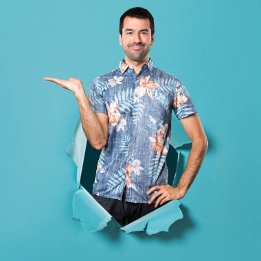 Bir şey mavi kağıt delik tutan çiçek forması ile yakışıklı adam