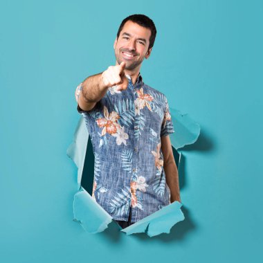 Açık mavi kağıt delikten işaret eden çiçek forması ile yakışıklı adam