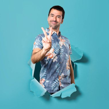Bir mavi kağıt delikten çiçek gömlek yapma zafer hareketi ile yakışıklı adam