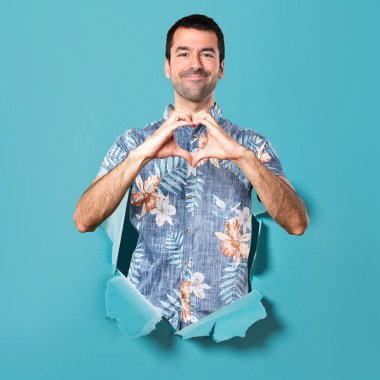 Elleri ile bir kalp mavi kağıt delik yapma çiçek forması ile yakışıklı adam