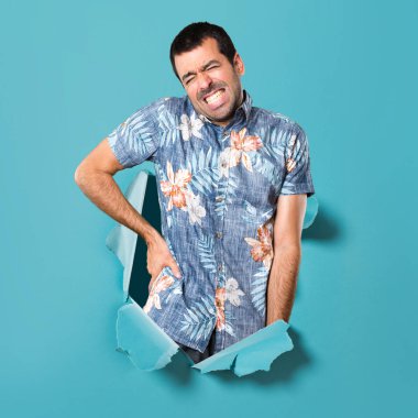 Bir mavi kağıt delikten sırt ağrısı ile çiçek gömlek ile yakışıklı adam