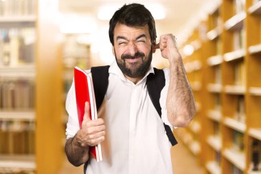 Kulakları ufuk kitaplığını kapsayan öğrenci adam