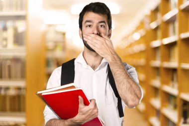 Ağzını ufuk kitaplığını kapsayan öğrenci adam