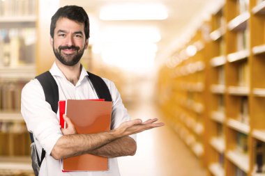 Ufuk kitaplığındaki bir şey sunan öğrenci adam