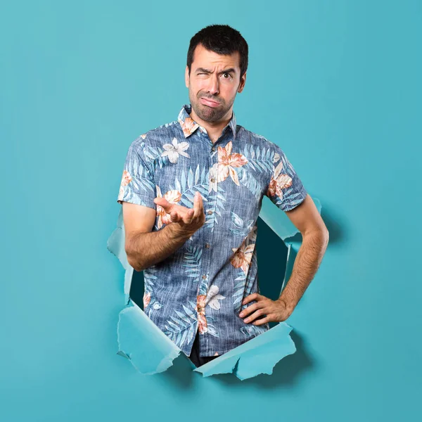 Bir mavi kağıt delikten çiçek forması ile yorgun yakışıklı adam