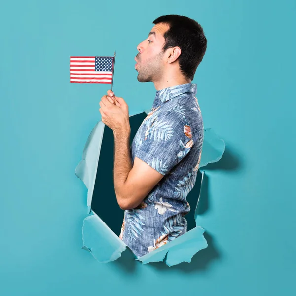 フラワー シャツ青紙の穴を通してアメリカの国旗を保持するいるとハンサムな男 — ストック写真