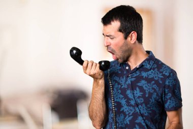 Esmer adam odada vintage telefona konuşuyor