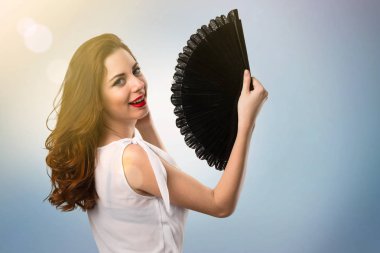 Mavi arka plan üzerinde bir fan ile mutlu güzel genç kız