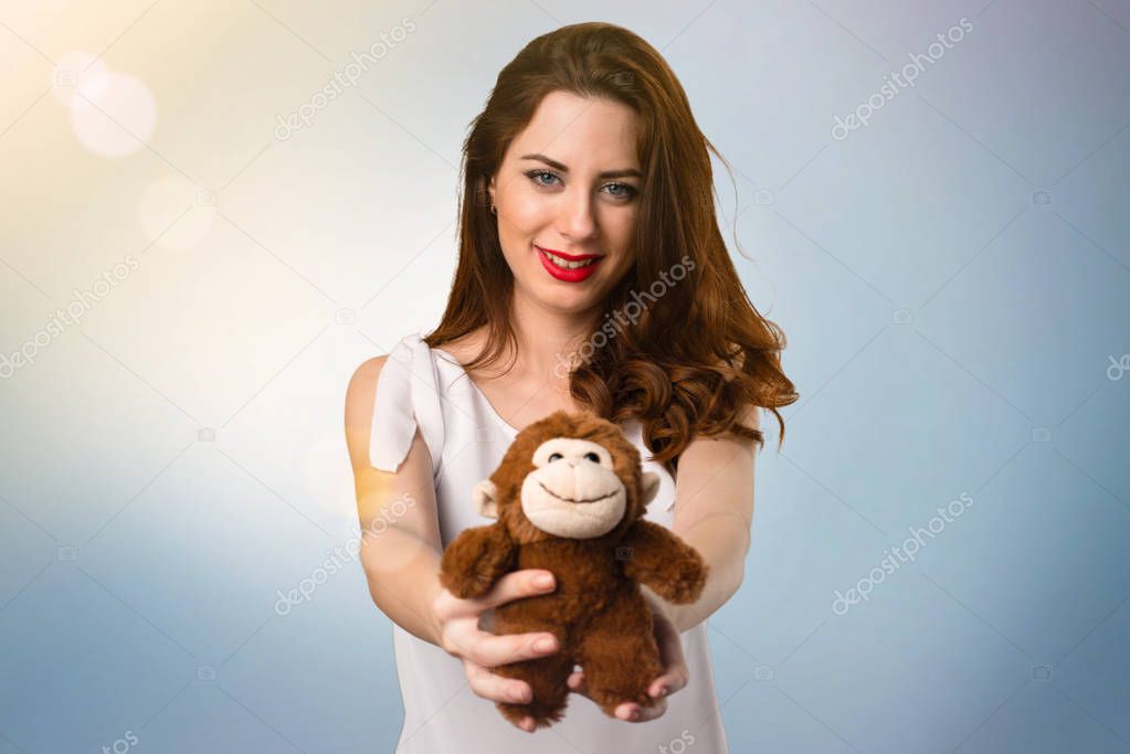 Beautiful young girl playing with a little stuffed animal on blue abstract background