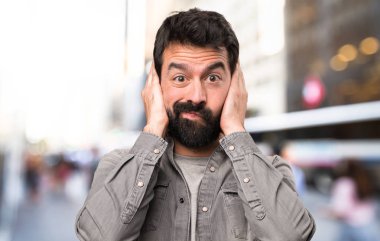 Kulaklarını açık, kapsayan sakallı yakışıklı adam