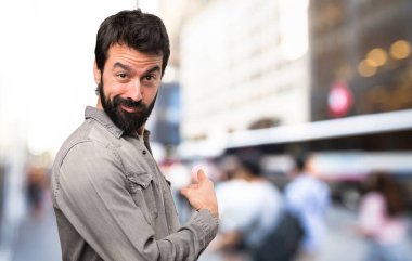 Geri, açık işaret eden sakallı yakışıklı adam