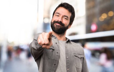 Ön tarafta açık işaret eden sakallı yakışıklı adam