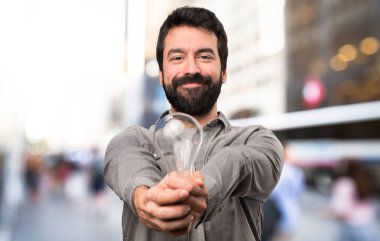 Bir ampul, açık tutarak sakallı yakışıklı adam