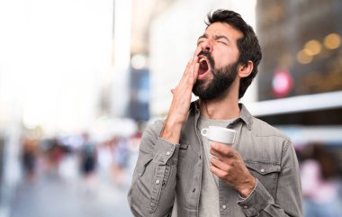 Bir fincan kahve, açık tutarak sakallı yakışıklı adam