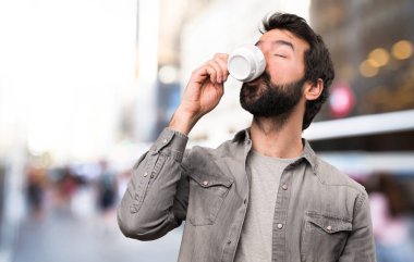 Bir fincan kahve, açık tutarak sakallı yakışıklı adam