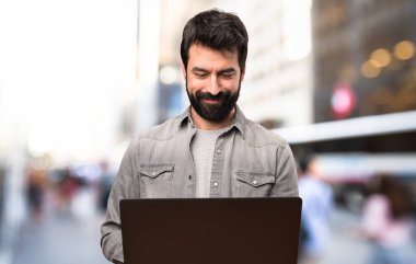 Dizüstü bilgisayar açık, sakallı yakışıklı adam