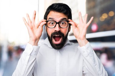 Yakışıklı adamla yapım sürpriz jest odaklanmamış arka plan üzerinde gözlük