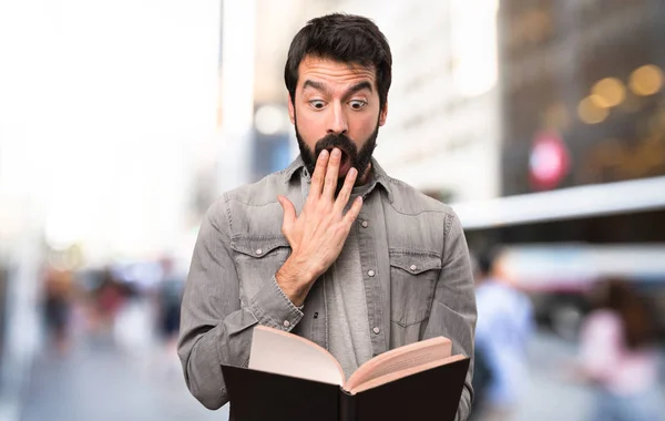 Surprised Handsome man with beard reading a book at outdoor