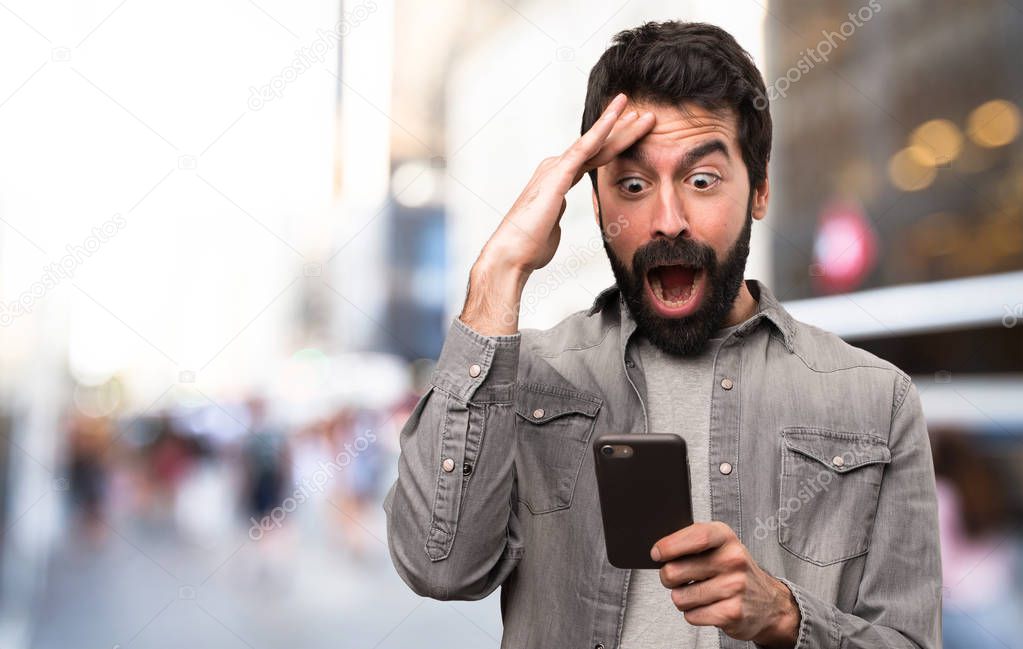 Surprised Handsome man with beard talking to mobile at outdoor