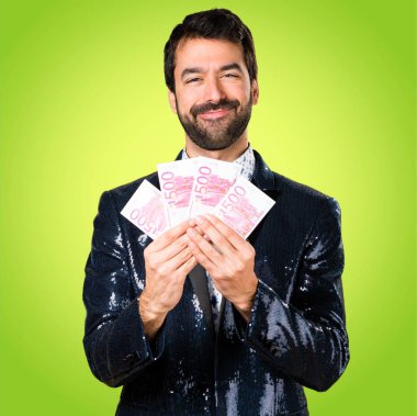 Adam renkli arka plan üzerinde bir sürü para alarak ceket ile