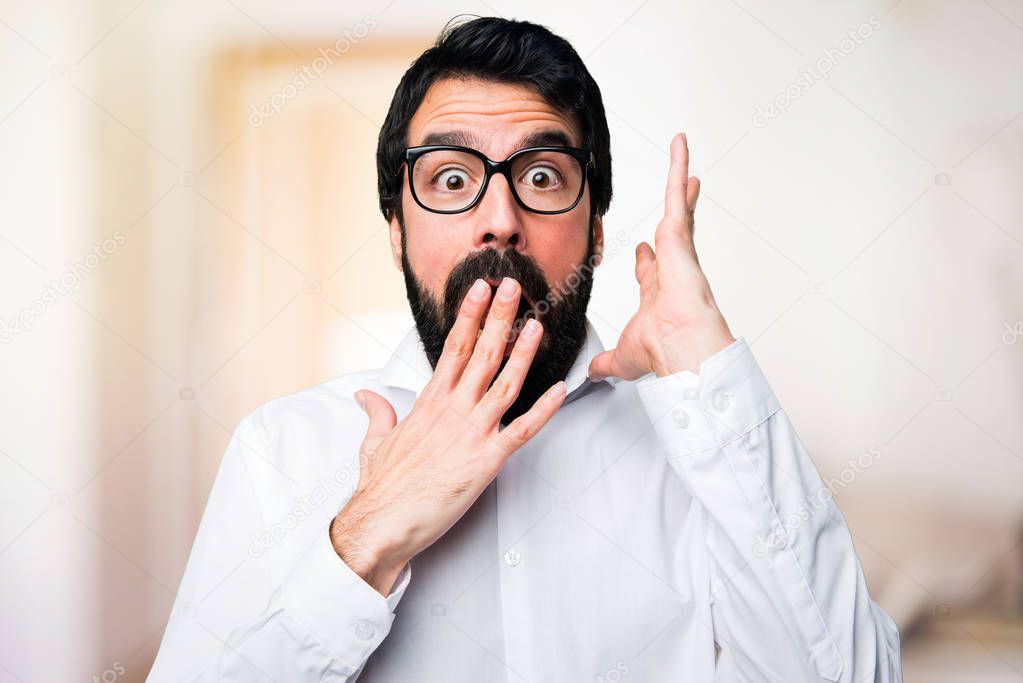 Handsome man with glasses making surprise gesture on unfocused background