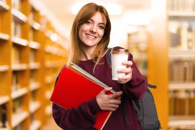 Bir fincan kahve odaklanmamış arka planda tutan öğrenci kadın