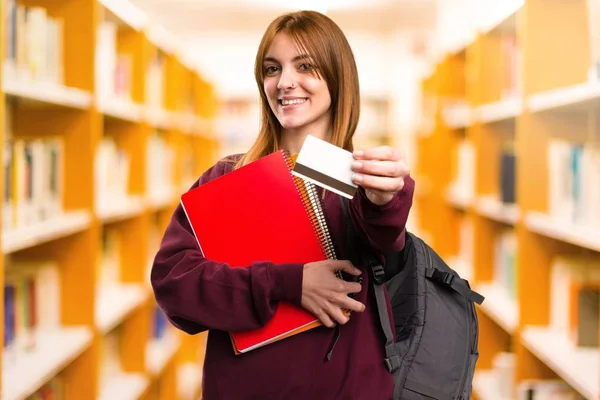 Student woman holding a credit card on unfocused background