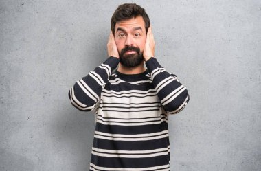 Kulakları dokulu arka plan üzerinde kapsayan sakallı