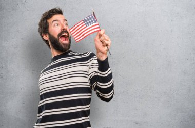 Bir Amerikan bayrağı dokulu arka plan üzerinde tutarak sakallı