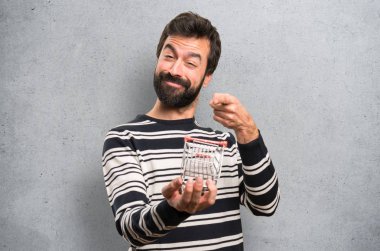 Mutlu bir adam ile bir süpermarket arabası oyuncak dokulu arka plan üzerinde tutarak sakal