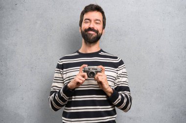 Sakallı bir kamera dokulu arka plan üzerinde tutarak mutlu adam