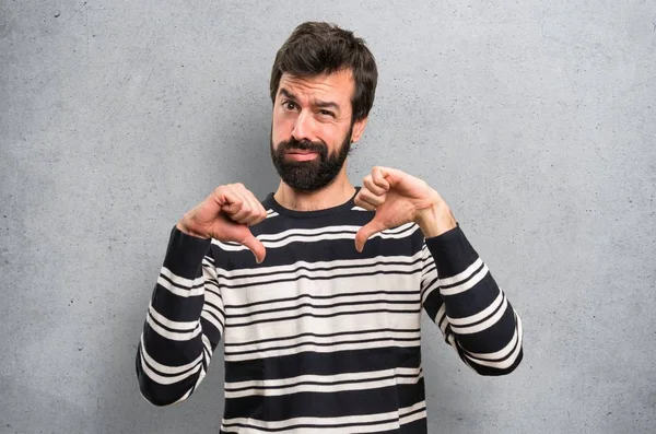 Man with beard making bad signal on textured background